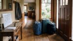 Going Away? Shut Off These Plumbing Risks Homeowner Turning A Brass Main Water Shut-Off Valve Before Leaving On Vacation